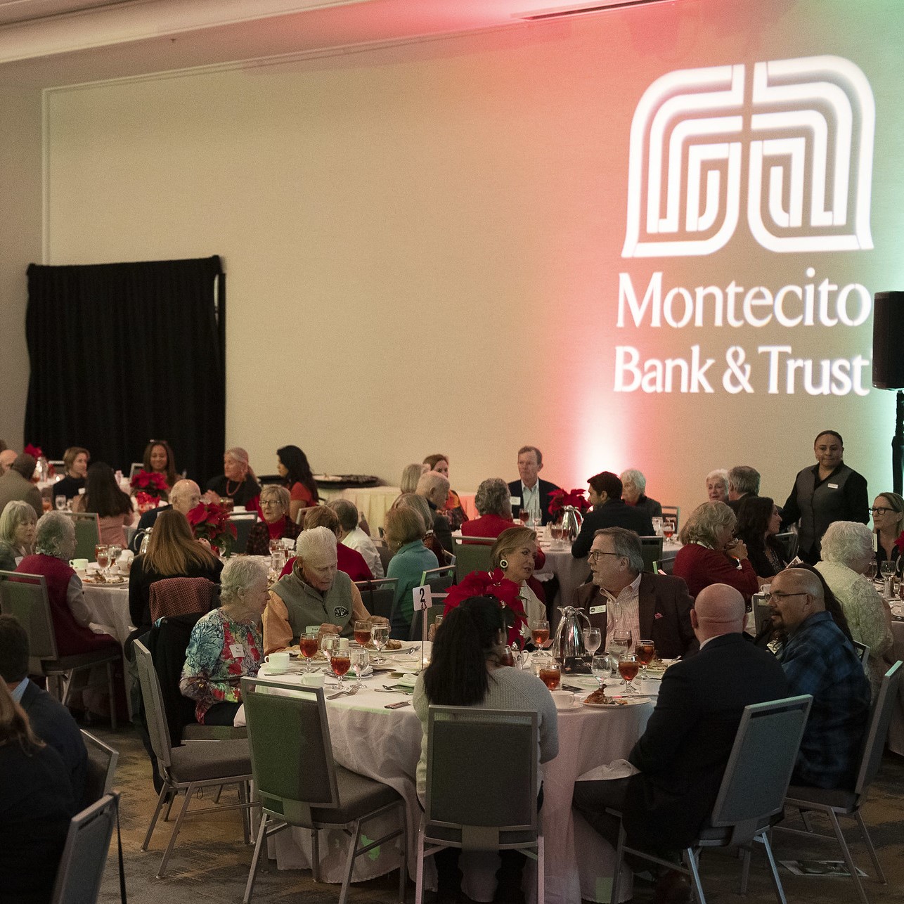CLL 2022 Attendees dining with Montecito Bank & Trust logo projected on the wall.
